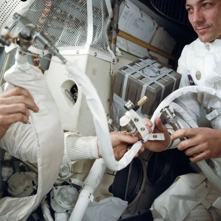 Jack Swigert in Aquarius beside a square canister, with Jim Lovell’s hands at left.