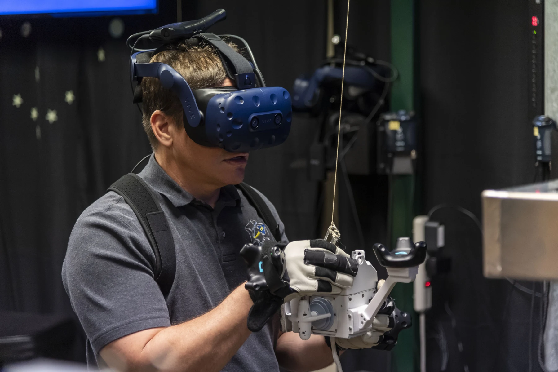 Bob Behnken wears a virtual-reality headset and holds the controls of a SAFER trainer.