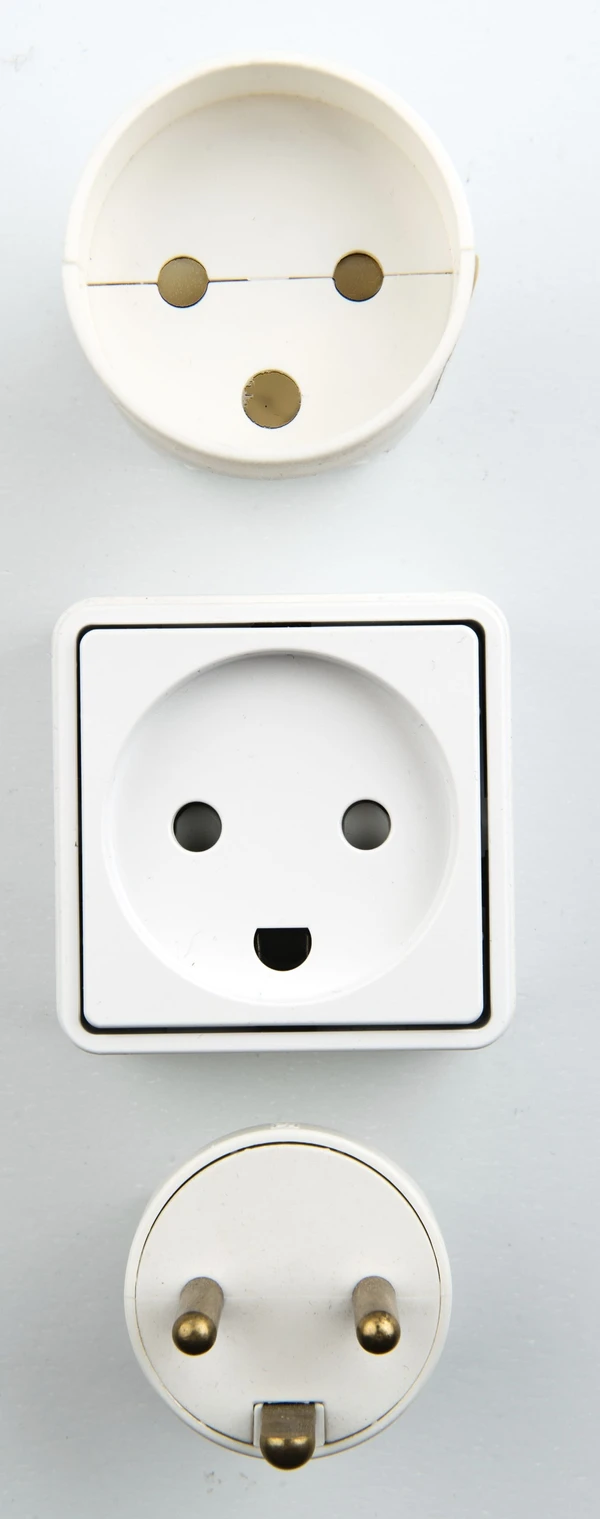 Danish electrical connectors arranged vertically: extension socket, wall outlet and plug.