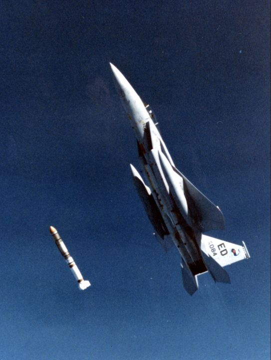 F-15 aircraft climbing steeply as a missile separates below it.