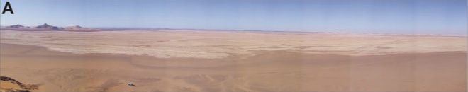 A dry, pale former lake bed stretches across the Garat Ouda basin beneath a blue sky.