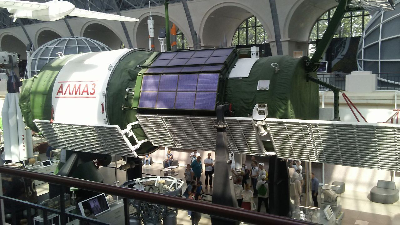 Green and white Almaz station exhibit with solar arrays in a Moscow museum.