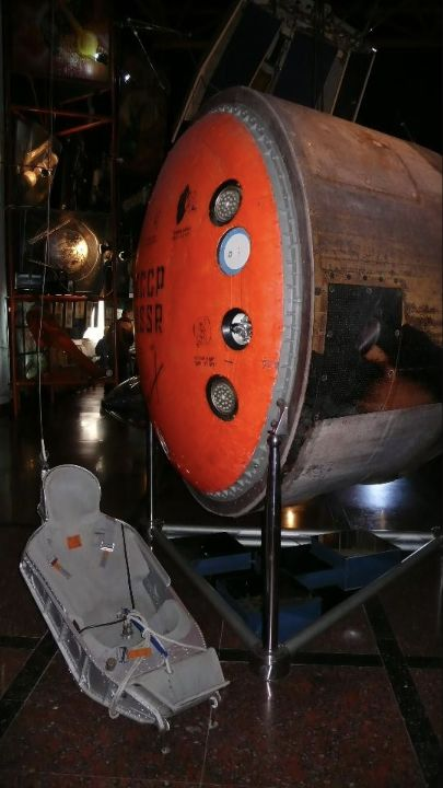 A scorched Soyuz reentry capsule and seat displayed in a museum.