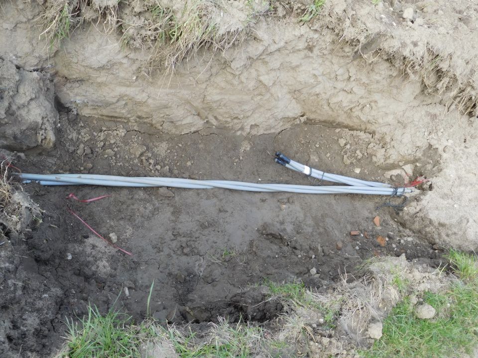 Three medium-voltage cables lie in an open trench.
