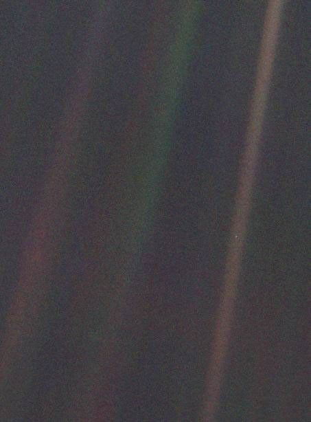 The original Pale Blue Dot view, with a tiny Earth near the middle of the rightmost bright streak in a grainy dark image.