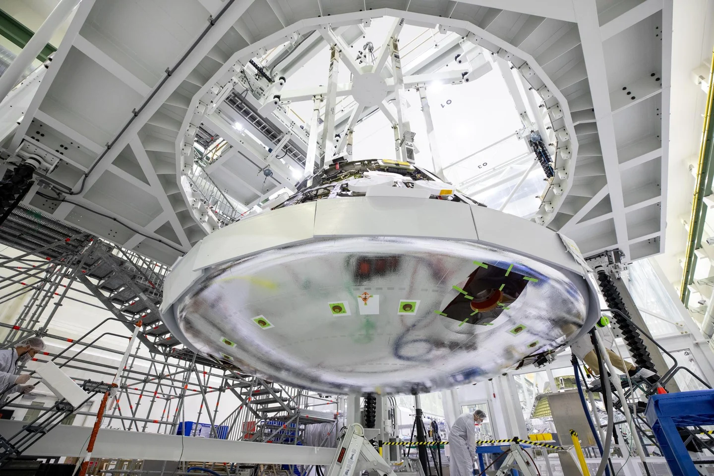 Orion’s broad circular heat shield is seen from below during installation in a high assembly fixture.
